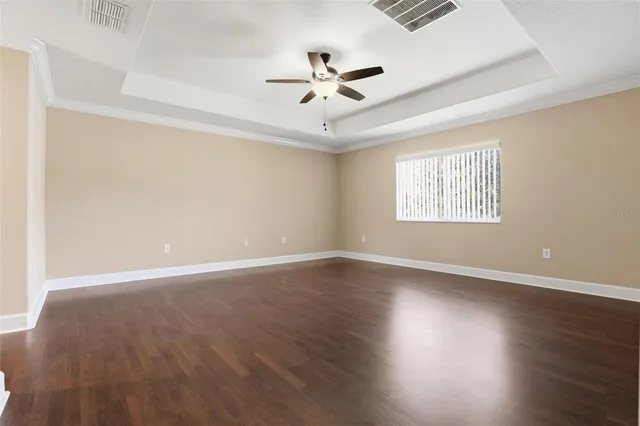 an empty room with wooden floor ceiling fan and windows