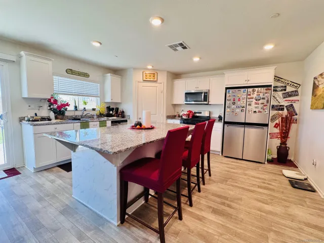 a kitchen with stainless steel appliances a dining table chairs refrigerator and sink