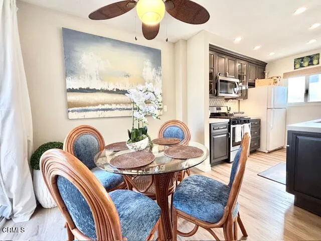 a dinning room with stainless steel appliances furniture a rug and a kitchen view