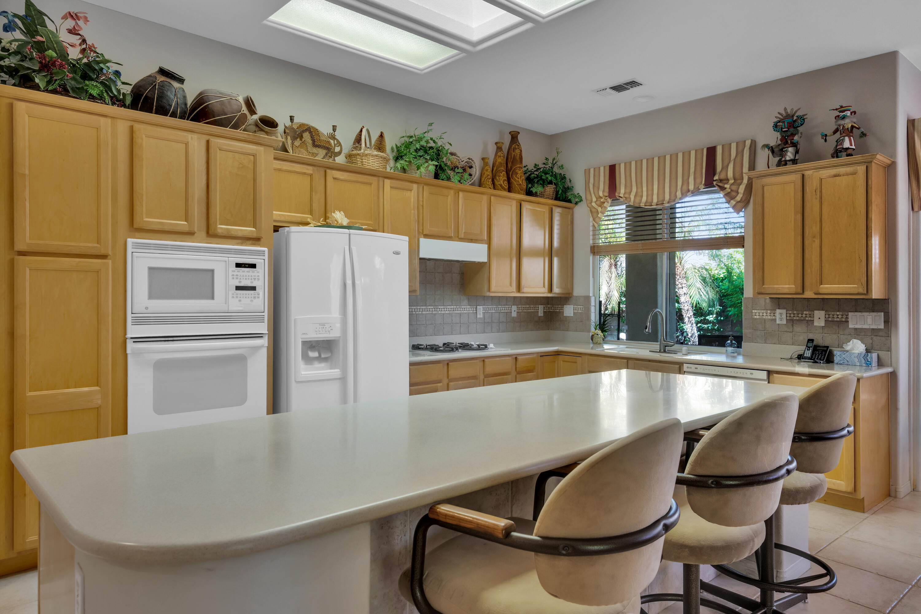 37384 Wyndham Road Palm Desert, CA 92211 - Photo 13 of 30 a kitchen with stainless steel appliances granite countertop a refrigerator a sink a stove and white cabinets