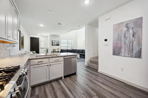 a large kitchen with a lot of counter space and wooden floor