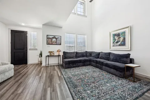 a living room with furniture kitchen view and a wooden floor