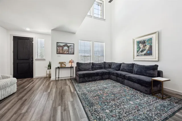 a living room with furniture kitchen view and a wooden floor