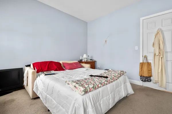 a bedroom with a bed and a flat tv screen on dresser