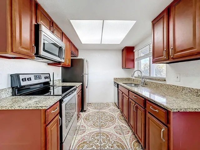 a kitchen with stainless steel appliances granite countertop a sink stove and cabinets