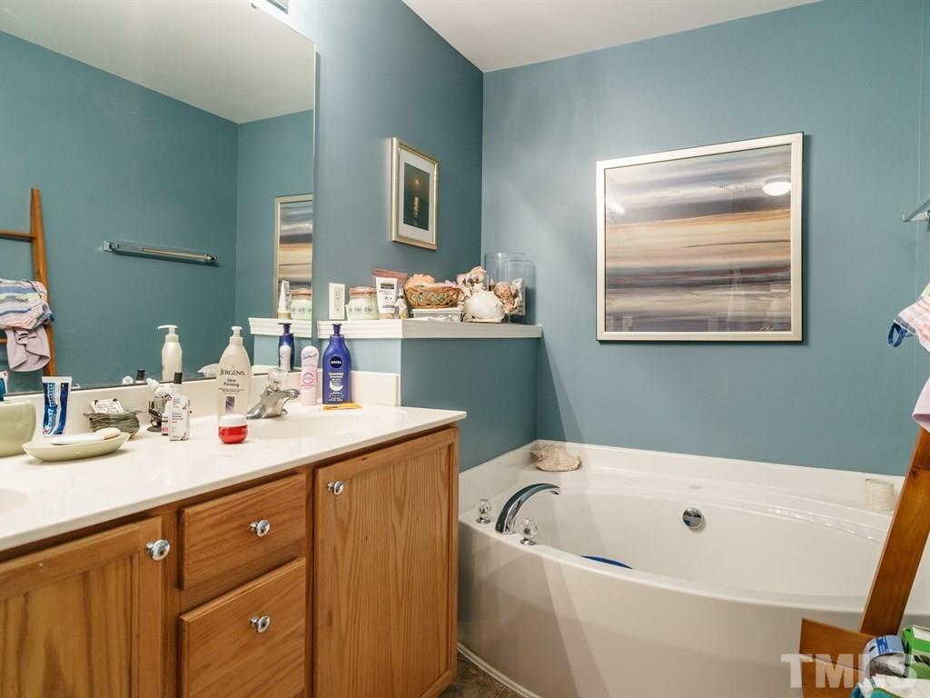 8411 Stonework Drive Raleigh, NC 27613 - Photo 14 of 19 a bathroom with a tub a sink and mirror