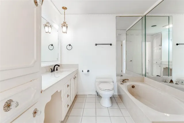 a large white bathroom with a granite countertop tub a toilet and a double vanity sink