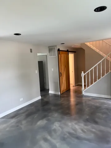 a view of an empty room with wooden floor and windows