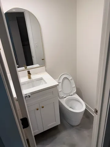 a bathroom with a granite countertop toilet sink and mirror
