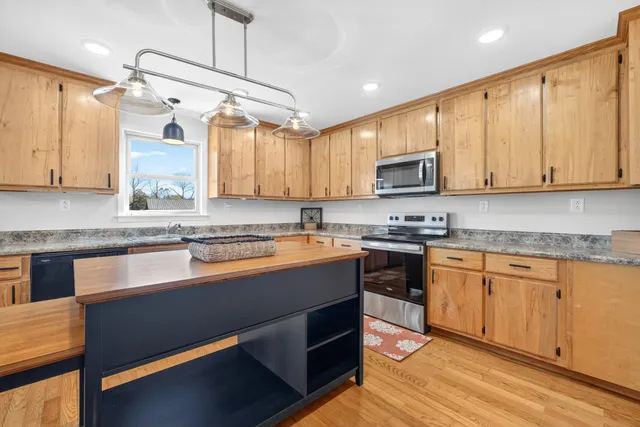 a kitchen with stainless steel appliances granite countertop a stove a sink and a microwave