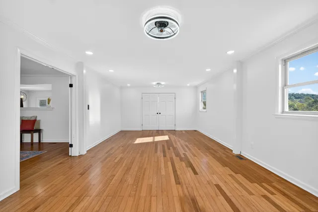 a view of empty room with wooden floor and window