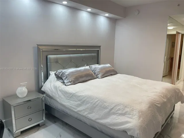 a large bed sitting in a bedroom and chandelier