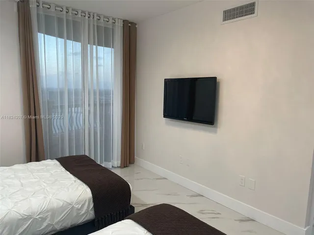 a bedroom with a bed and a flat tv screen on the dresser