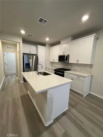 a large white kitchen with wooden floor and a sink