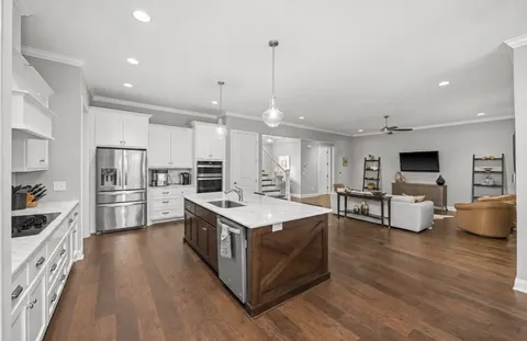 a large kitchen with stainless steel appliances kitchen island granite countertop a large island a stove a refrigerator a sink dishwasher and a dining table with wooden floor