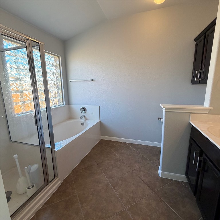 1115 Sunny Meadows Loop Georgetown, TX 78626 - Photo 17 of 36 Bathroom with vaulted ceiling, a garden tub, vanity, a shower stall, and dark tile patterned flooring