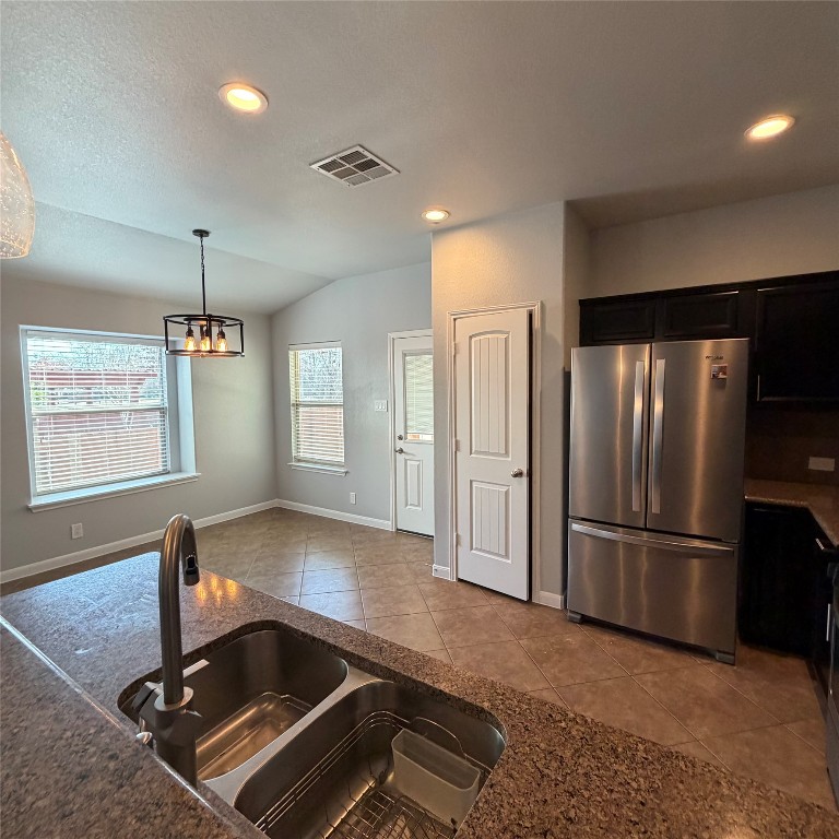 1115 Sunny Meadows Loop Georgetown, TX 78626 - Photo 21 of 36 Kitchen with freestanding refrigerator, tile patterned flooring, vaulted ceiling, recessed lighting, and pendant lighting