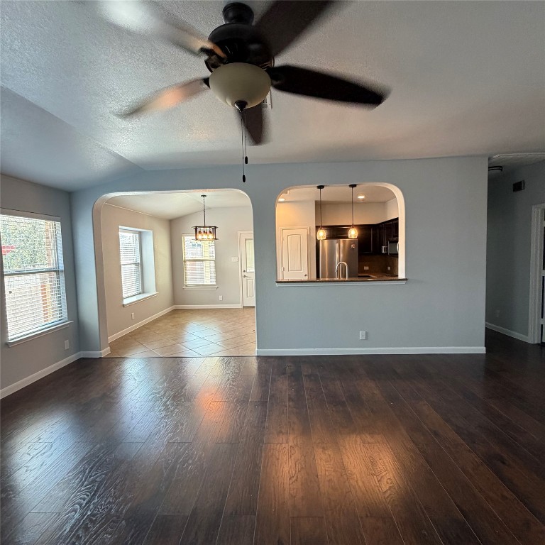 1115 Sunny Meadows Loop Georgetown, TX 78626 - Photo 23 of 36 Unfurnished living room with vaulted ceiling, arched walkways, a textured ceiling, plenty of natural light, and a ceiling fan