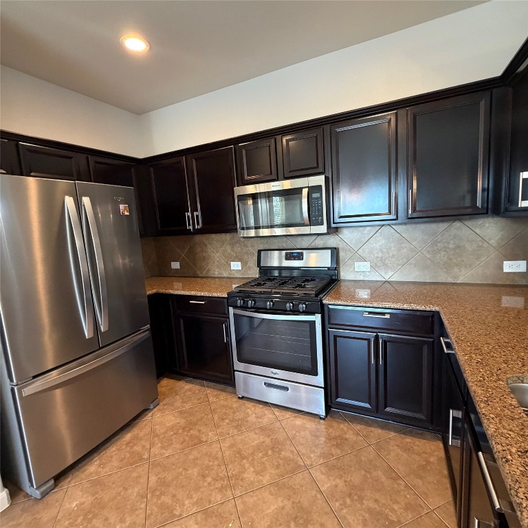 1115 Sunny Meadows Loop Georgetown, TX 78626 - Photo 27 of 36 Kitchen with appliances with stainless steel finishes, light stone countertops, light tile patterned floors, backsplash, and recessed lighting