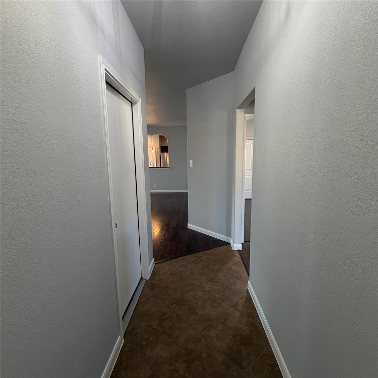 1115 Sunny Meadows Loop Georgetown, TX 78626 - Photo 4 of 36 Corridor featuring arched walkways, a textured wall, and dark tile patterned floors