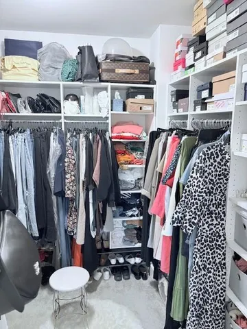 a walk in closet with clothes and shoes