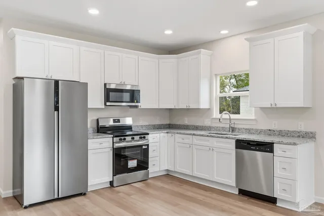 a kitchen with white cabinets and stainless steel appliances