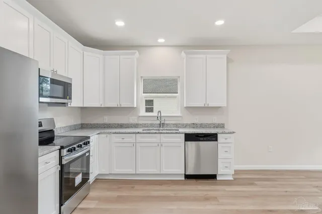 a kitchen with granite countertop white cabinets and stainless steel appliances