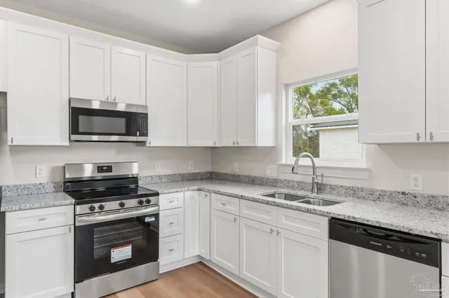 a kitchen with granite countertop white cabinets and a stove