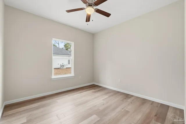 an empty room with window and a ceiling fan
