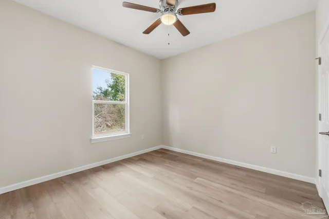 an empty room with a window and a ceiling fan