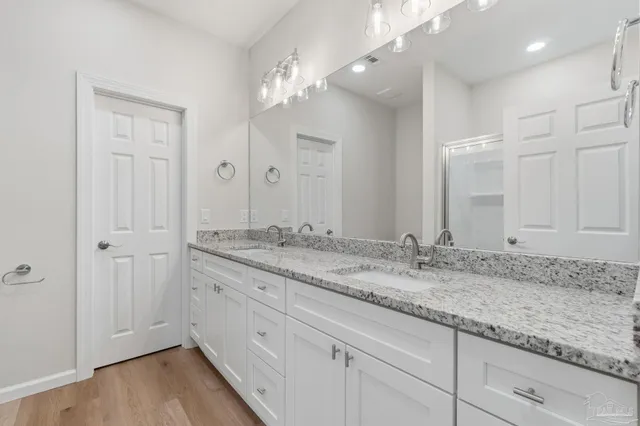 a bathroom with a granite countertop double vanity sink and mirror