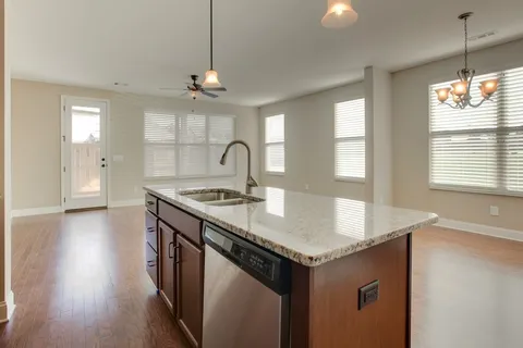 a kitchen with a sink a chandelier stainless steel appliances and window