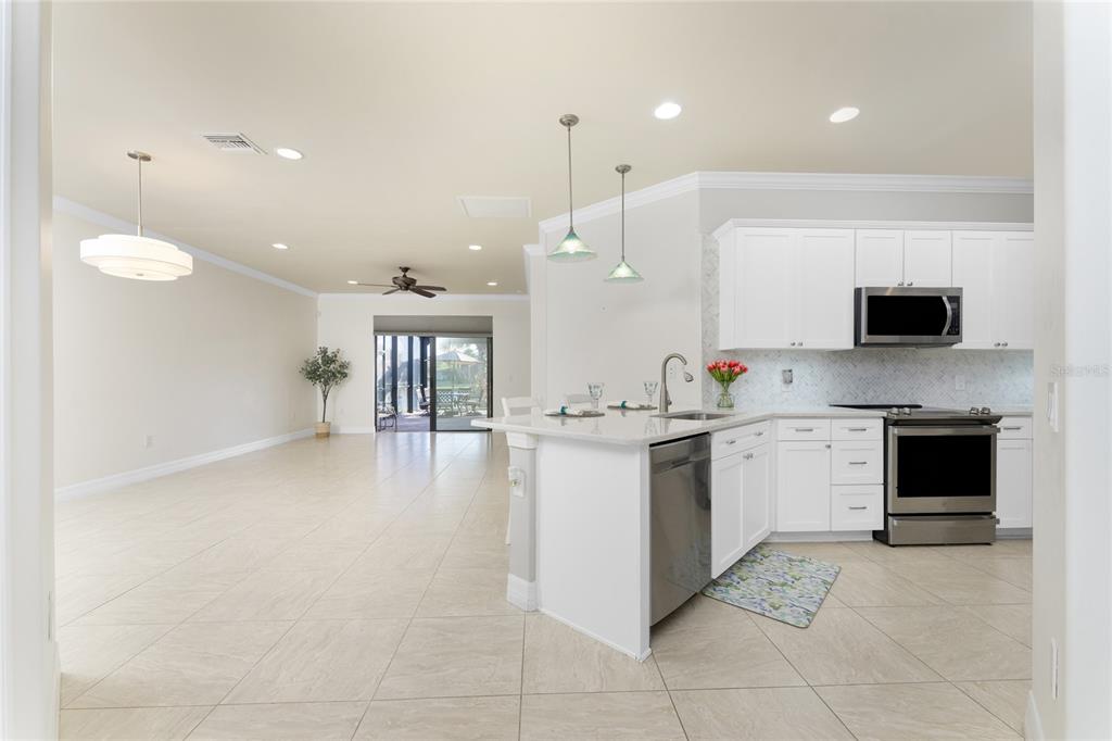 13869 Alafaya Street Venice, FL 34293 - Photo 16 of 75 a large white kitchen with a sink and dishwasher a stove top oven with wooden floor