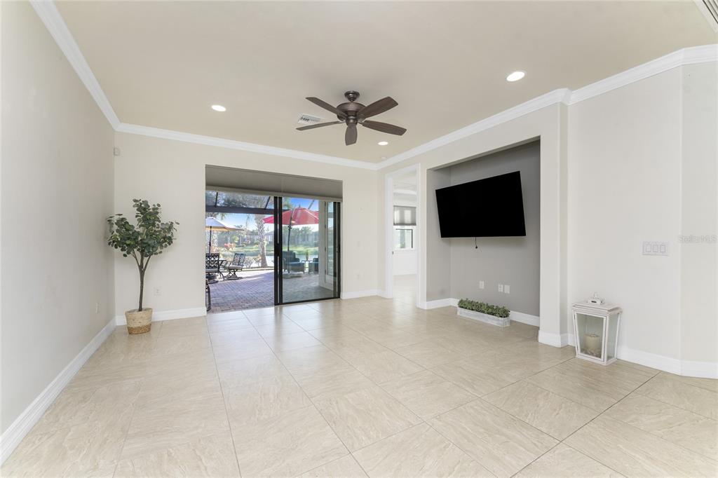 13869 Alafaya Street Venice, FL 34293 - Photo 20 of 75 a view of a livingroom with a flat screen tv potted plant and a ceiling fan
