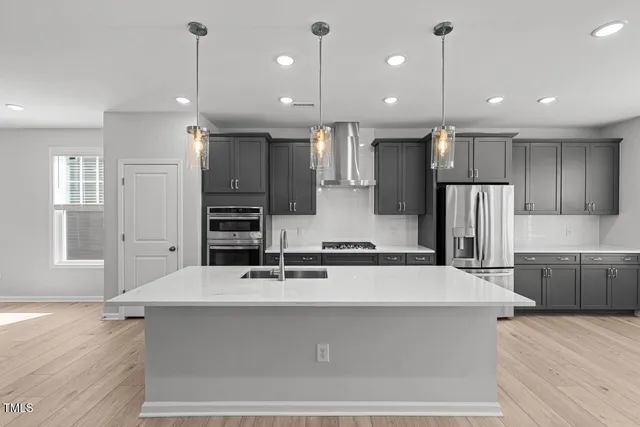 a large kitchen with a large counter top a sink stainless steel appliances and cabinets