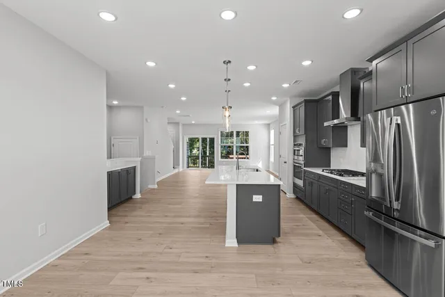 a large kitchen with stainless steel appliances a large counter top and a refrigerator