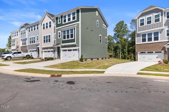 a view of residential houses with yard and road