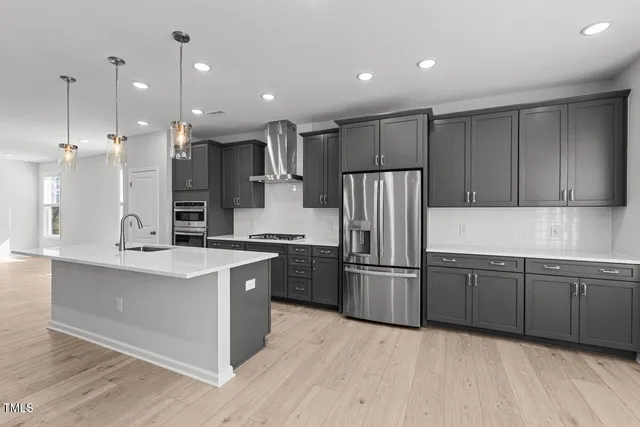 a kitchen with stainless steel appliances granite countertop a refrigerator a sink and a stove