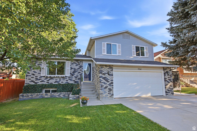 734 Sandy Dunes Drive Sandy, UT 84094 - Photo 1 of 36 Cute exterior featuring a two-car garage, light blue siding, and multi-tone brick accents