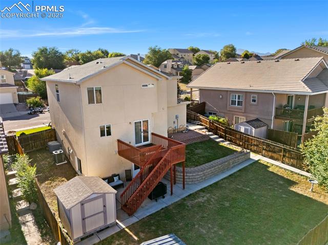 712 Rye Ridge Road Fountain, CO 80817 - Photo 42 of 45 Back of property featuring stairs, a storage shed, a patio, stucco siding, and a residential view