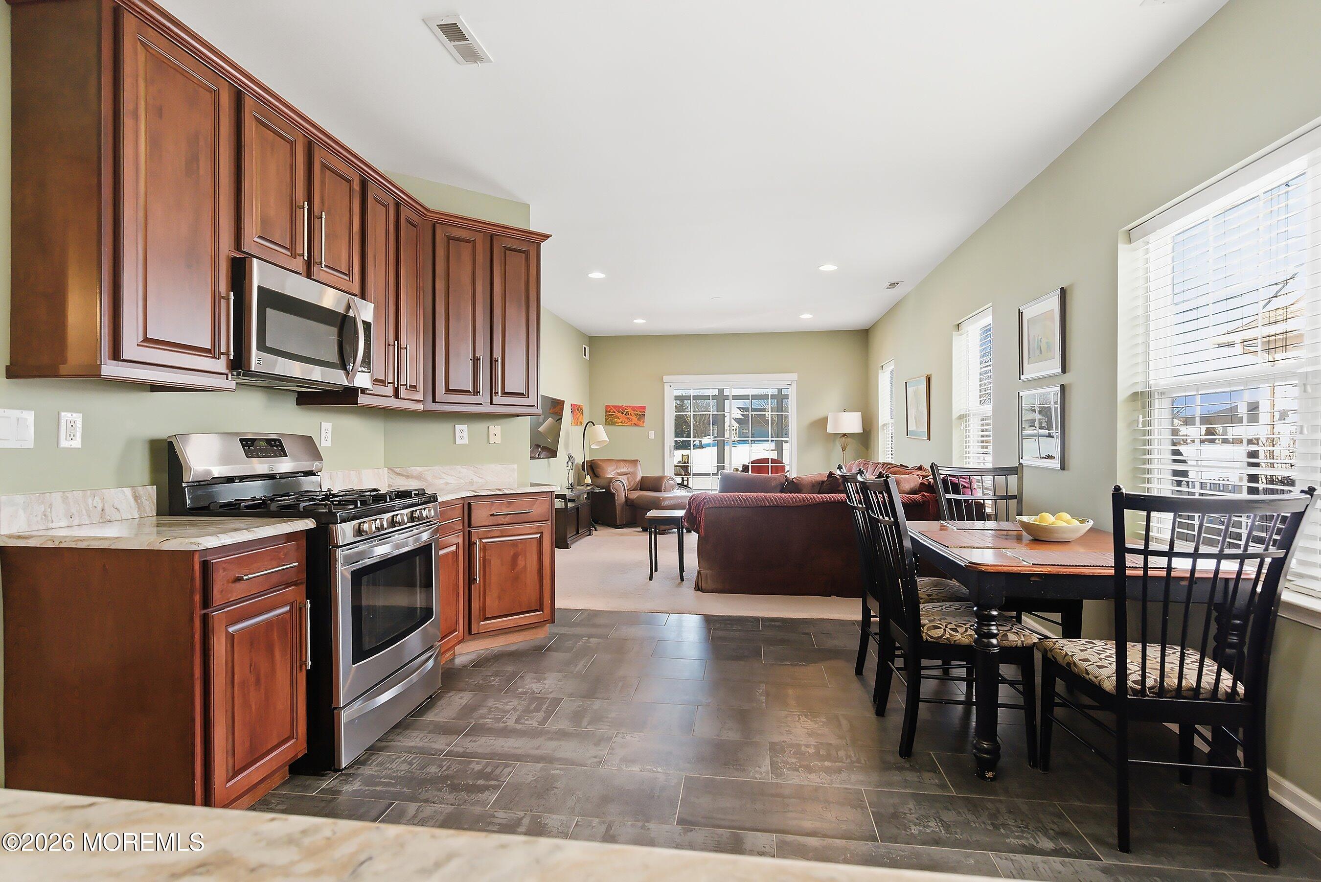 10 Arcadia Drive Manchester Township, NJ 08759 - Photo 6 of 37 a kitchen with stove a sink dishwasher a dining table and chairs with wooden floor