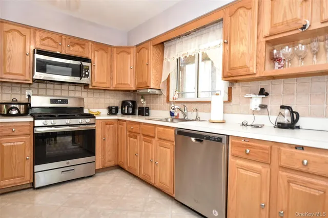 a kitchen with stainless steel appliances granite countertop white cabinets a sink and a window