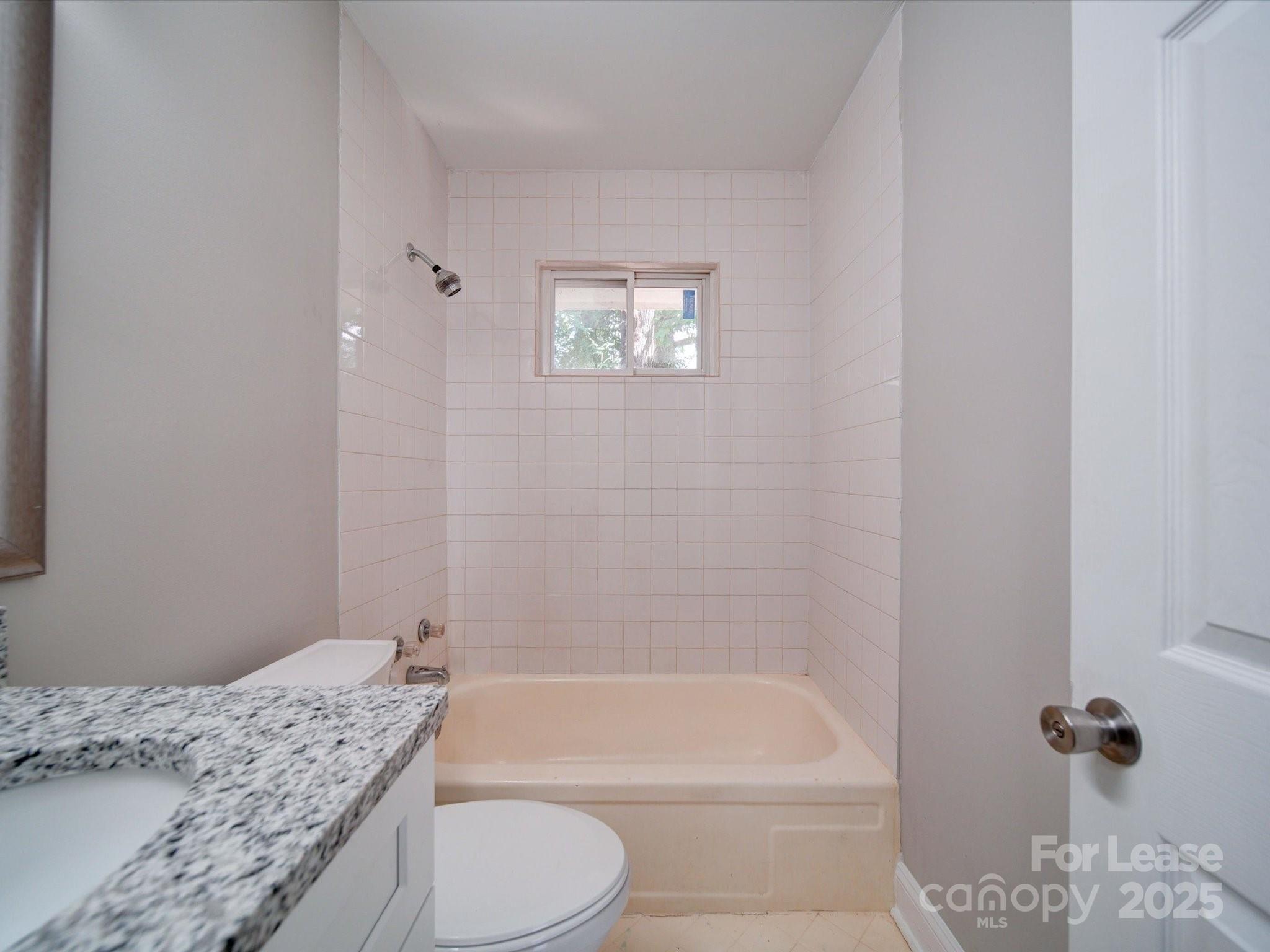 321 South Gardner Avenue, Unit 6 Charlotte, NC 28208 - Photo 26 of 35 a bathroom with a granite countertop toilet a sink and bathtub