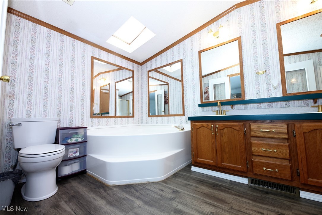 211 Gibson Road New Cumberland, WV 26047 - Photo 18 of 46 Bathroom with dark wood-style flooring, double vanity, ornamental molding, wallpapered walls, and a garden tub