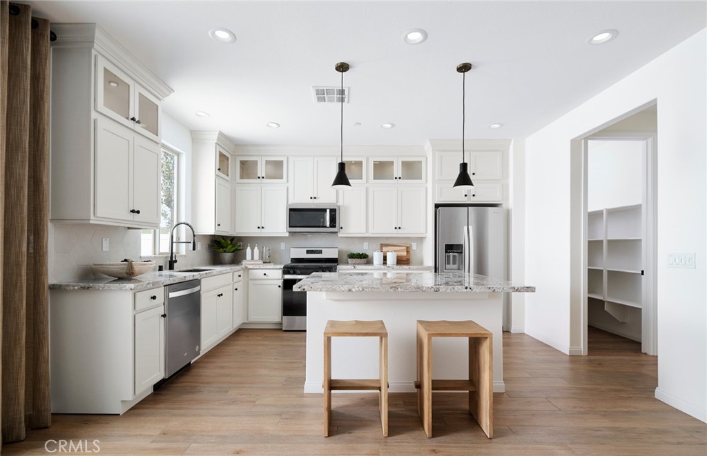 8141 Tristan Lane Riverside, CA 92507 - Photo 15 of 15 a kitchen with stainless steel appliances kitchen island granite countertop a table chairs and a refrigerator