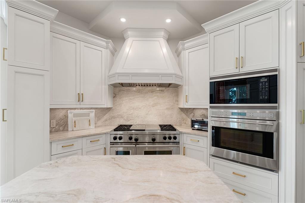 248 Point Salerno Naples, FL 34108 - Photo 13 of 42 a kitchen with white cabinets and stainless steel appliances