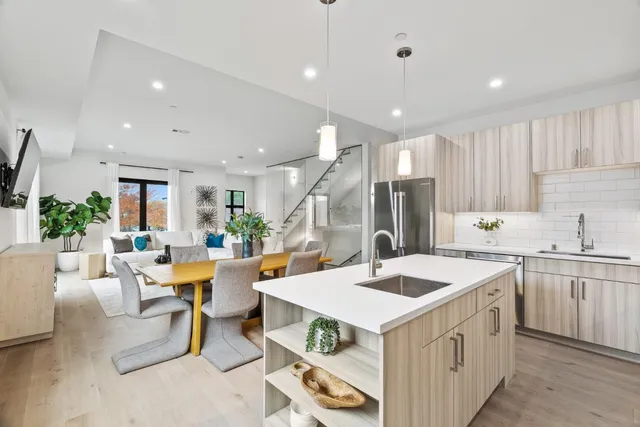 a kitchen with a stove a sink a kitchen island and couches with wooden floor