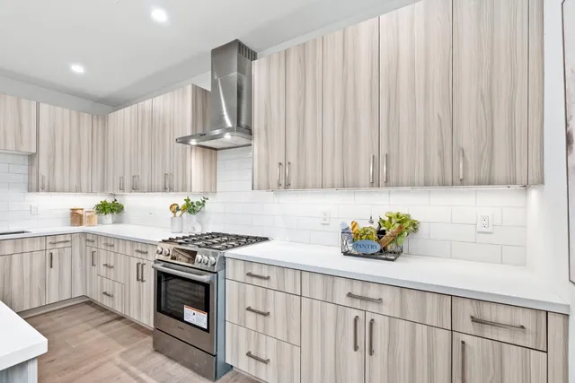 a kitchen with stainless steel appliances a sink a stove cabinets and a window