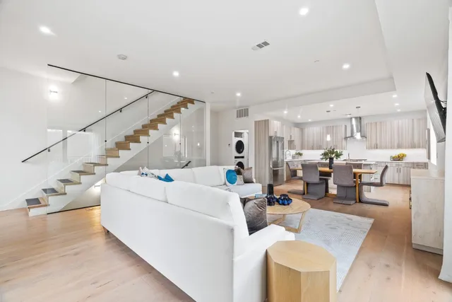 a living room with furniture and kitchen view with wooden floor