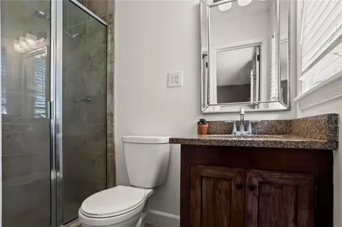 a bathroom with a granite countertop toilet sink and mirror